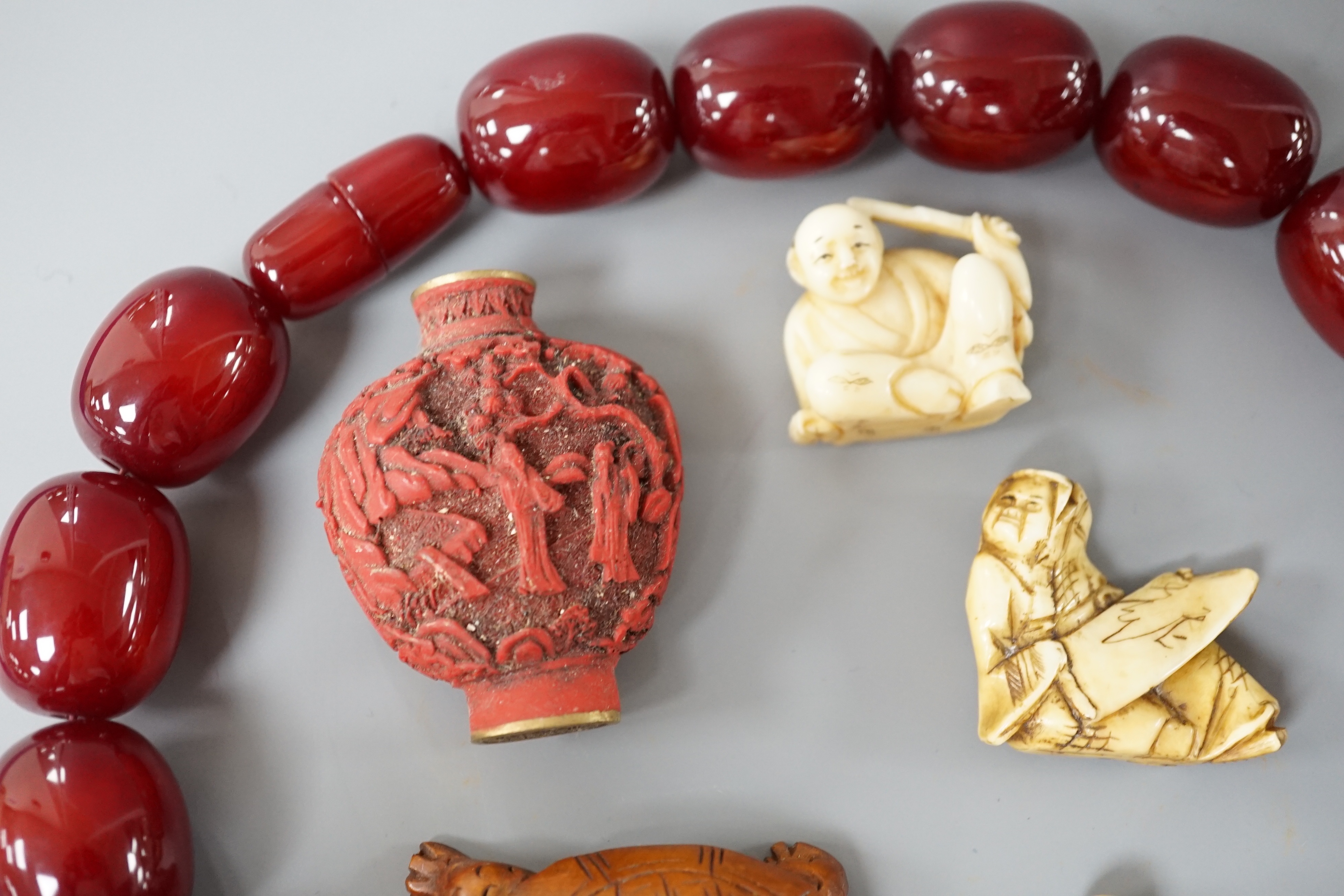 Assorted Chinese and Japanese Ivory and wood carvings, a scent bottle and a simulated cherry amber bead necklace, Necklace 52 cms long.